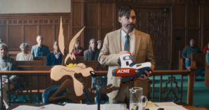 Wile E. Coyote sitzt neben einem Anwalt mit einem Acme-Produkt in einem Gerichtssaal.